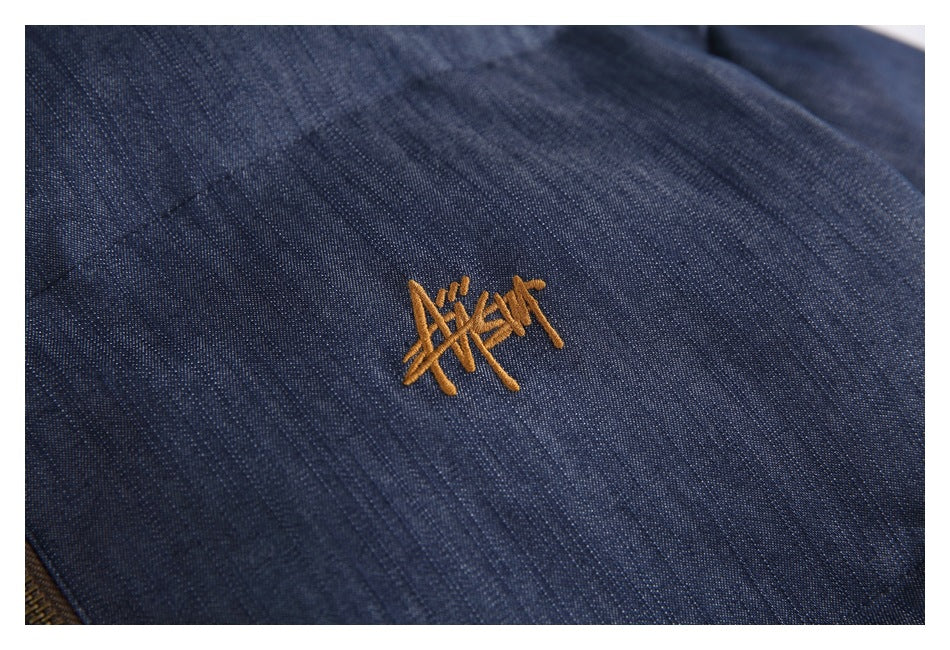 Close-up of a small gold embroidered emblem on dark blue jacket fabric.