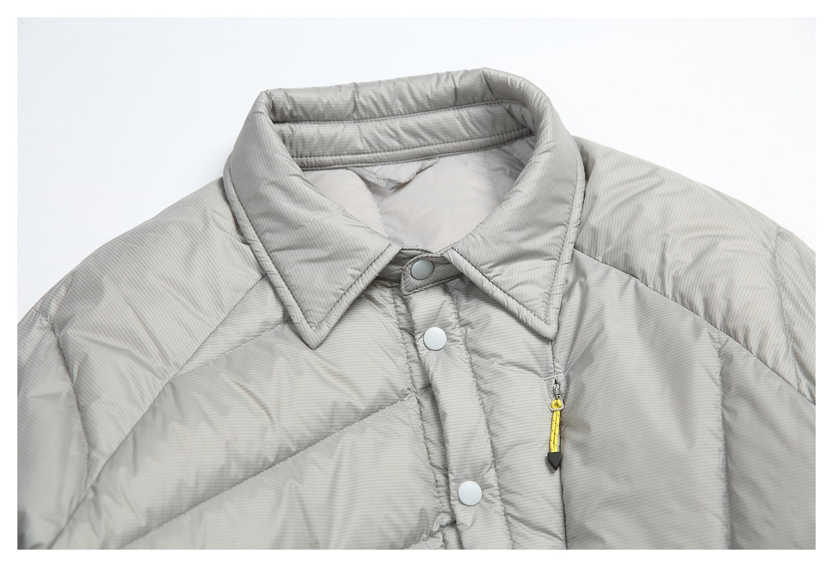 Close-up of the gray puffer jacket's pointed collar, top snaps, and yellow zipper pull.