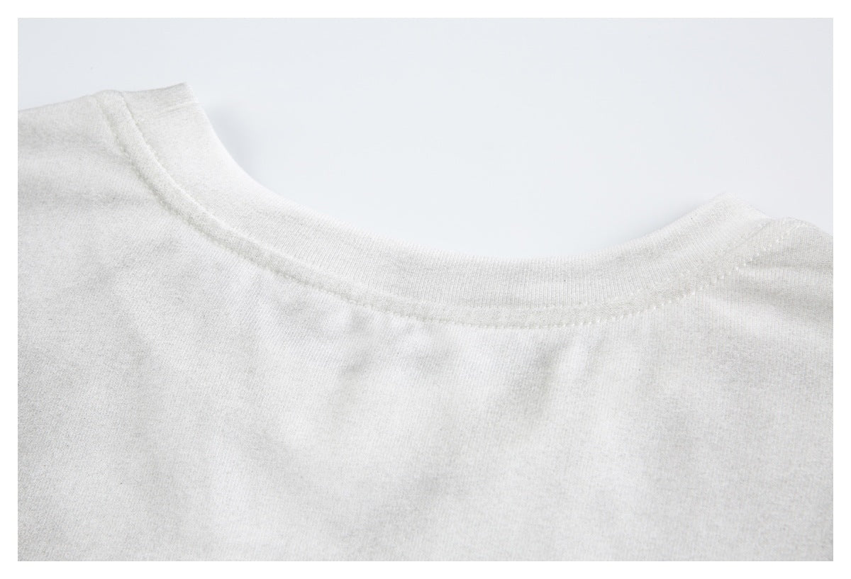 Close-up of the off-white shirt's crew neckline and shoulder stitching.