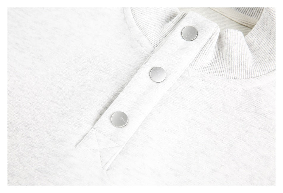 Close-up of a light heather gray garment's three-snap tab, neckline trim, and stitching.