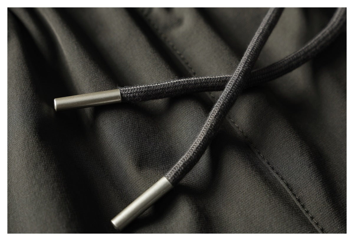 Close-up of dark charcoal garment drawstrings with silver-colored tips against the fabric.