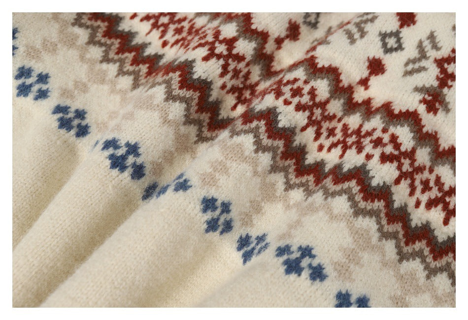 Close-up of cream knit fabric with red, gray, and blue geometric motifs.