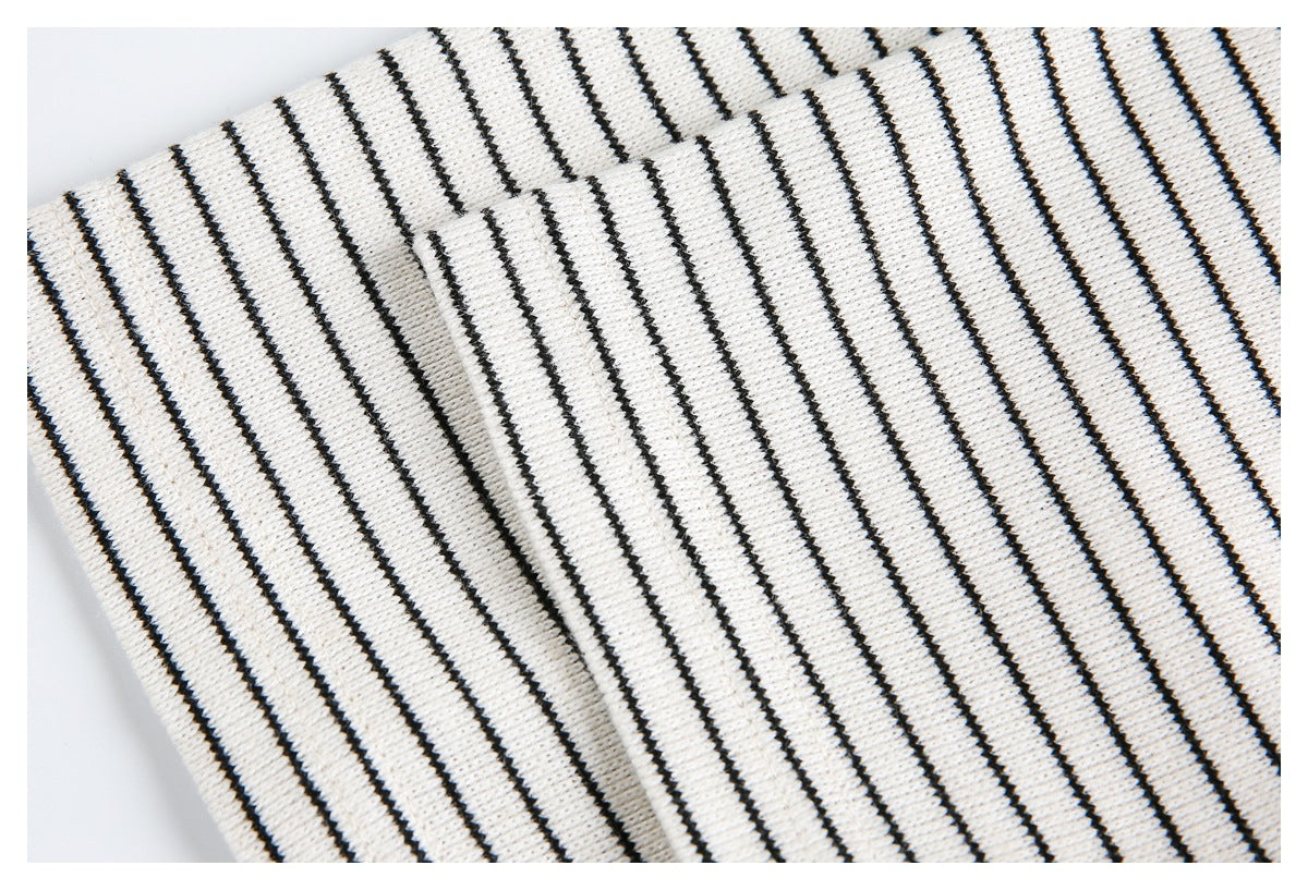 Close-up of folded cream knit fabric with narrow black stripes and a visible edge.