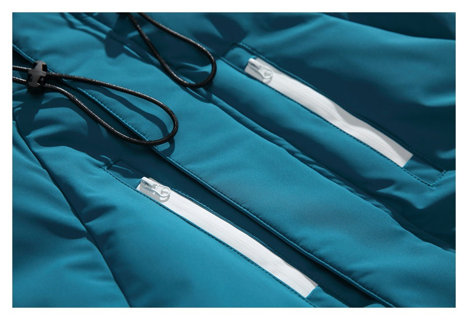 Close-up of two white zip pockets and black drawcords on the teal jacket.