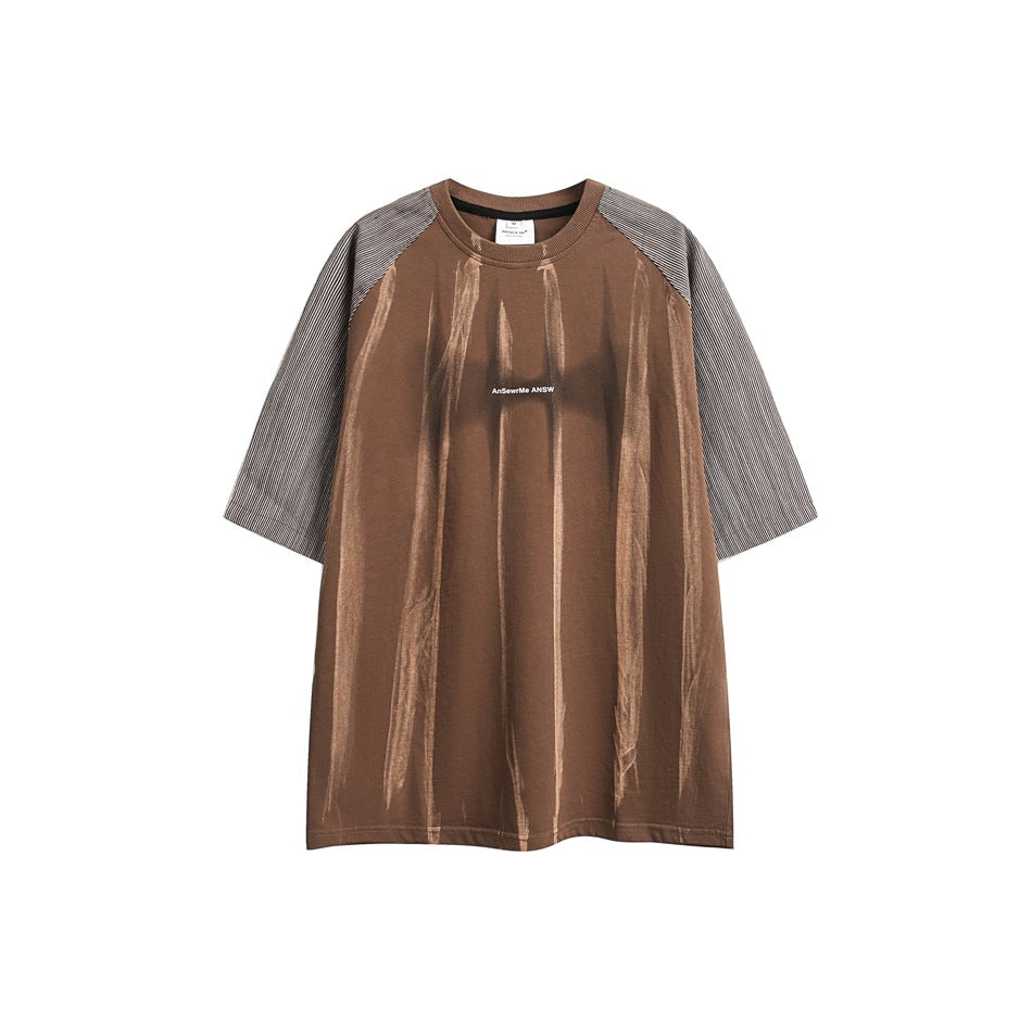 Front view of a brown oversized T-shirt with striped raglan sleeves, pale vertical streaks, and small white chest lettering.
