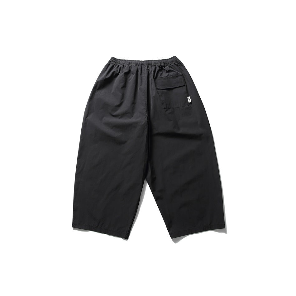 Black wide-leg cropped pants, flat lay back view with flap pocket and elastic waistband