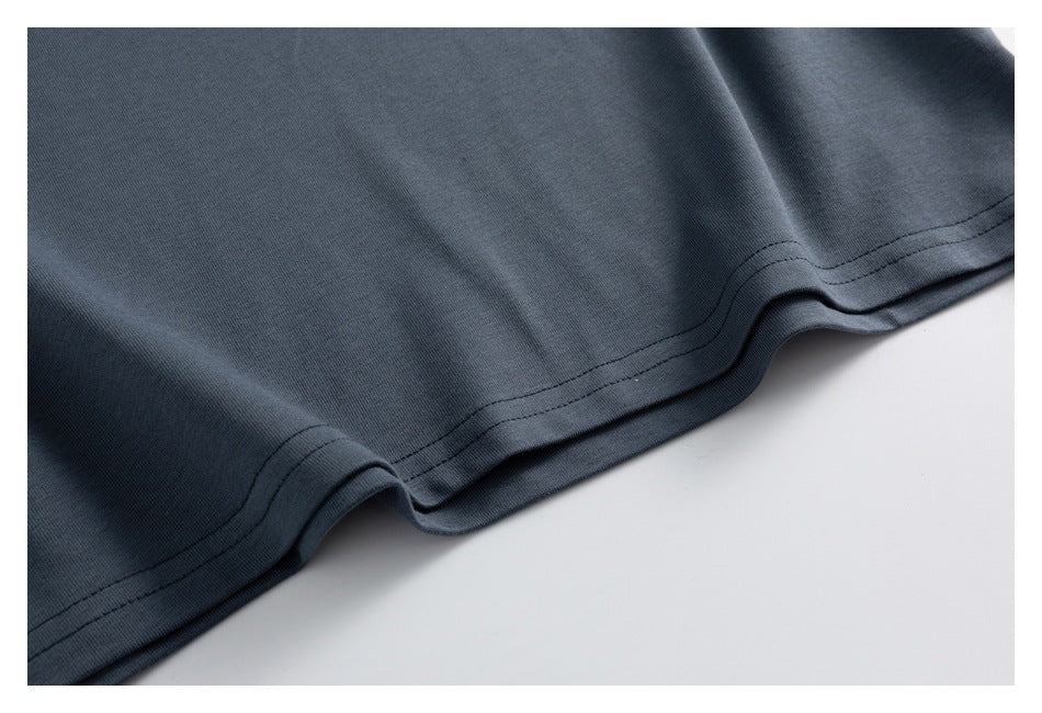 Close-up of the double-stitched bottom hem on a dark slate-gray garment.