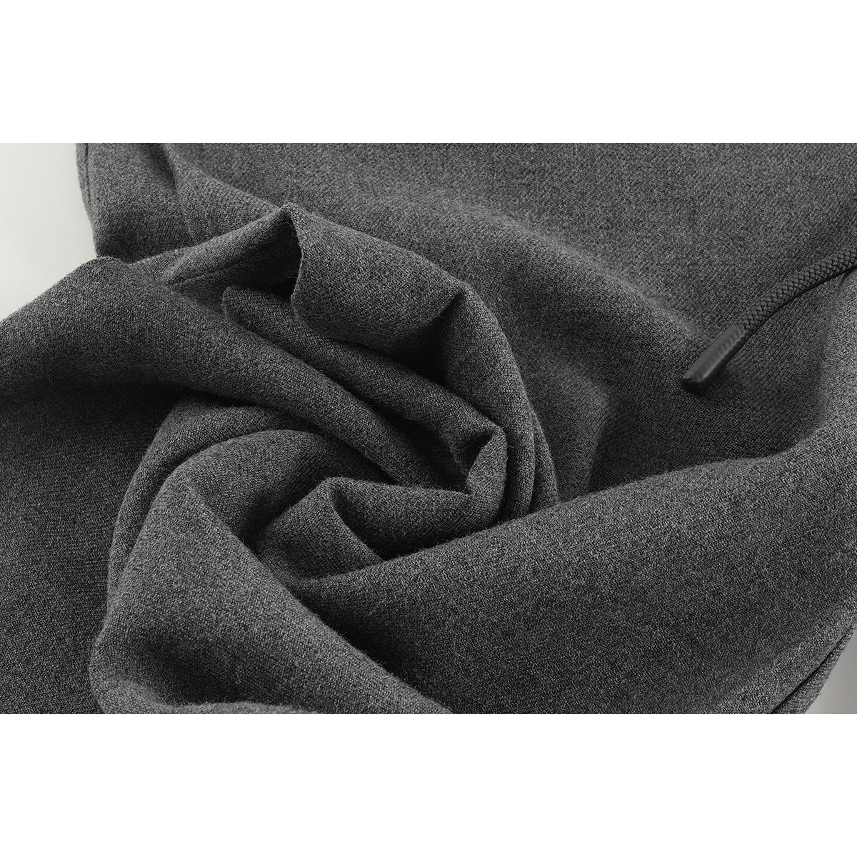 Close-up of charcoal gray pants showing the textured fabric, folds, and a small black tab.