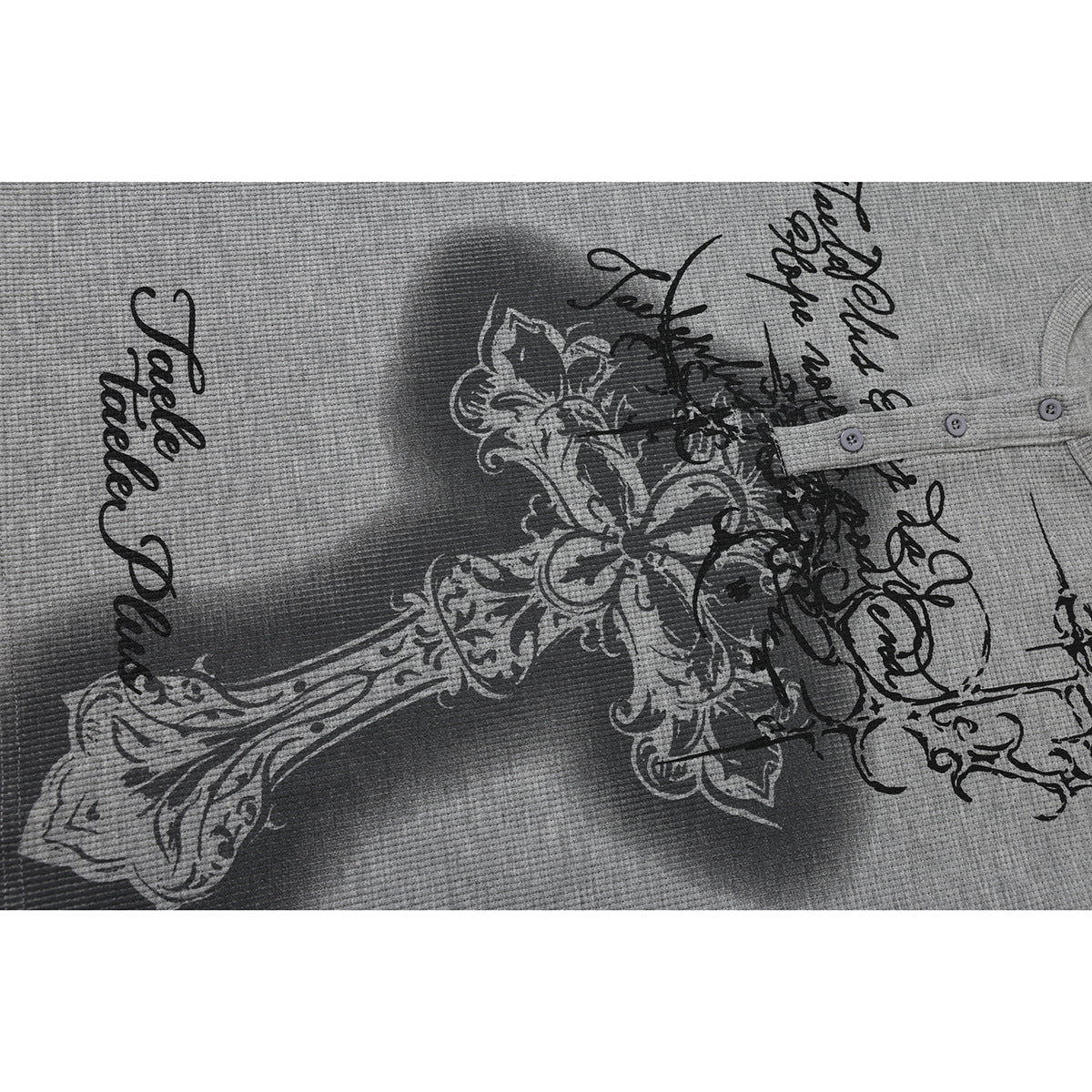 Close-up of a gray waffle-knit shirt with ornate black and white script and floral graphics.