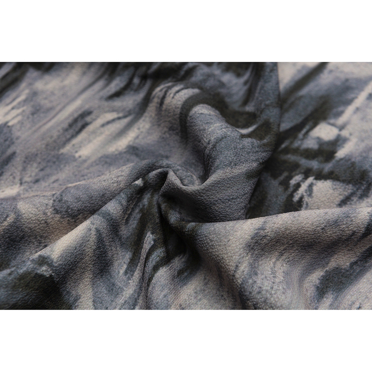 Close-up of the gray and black abstract-print shirt fabric gathered into folds.