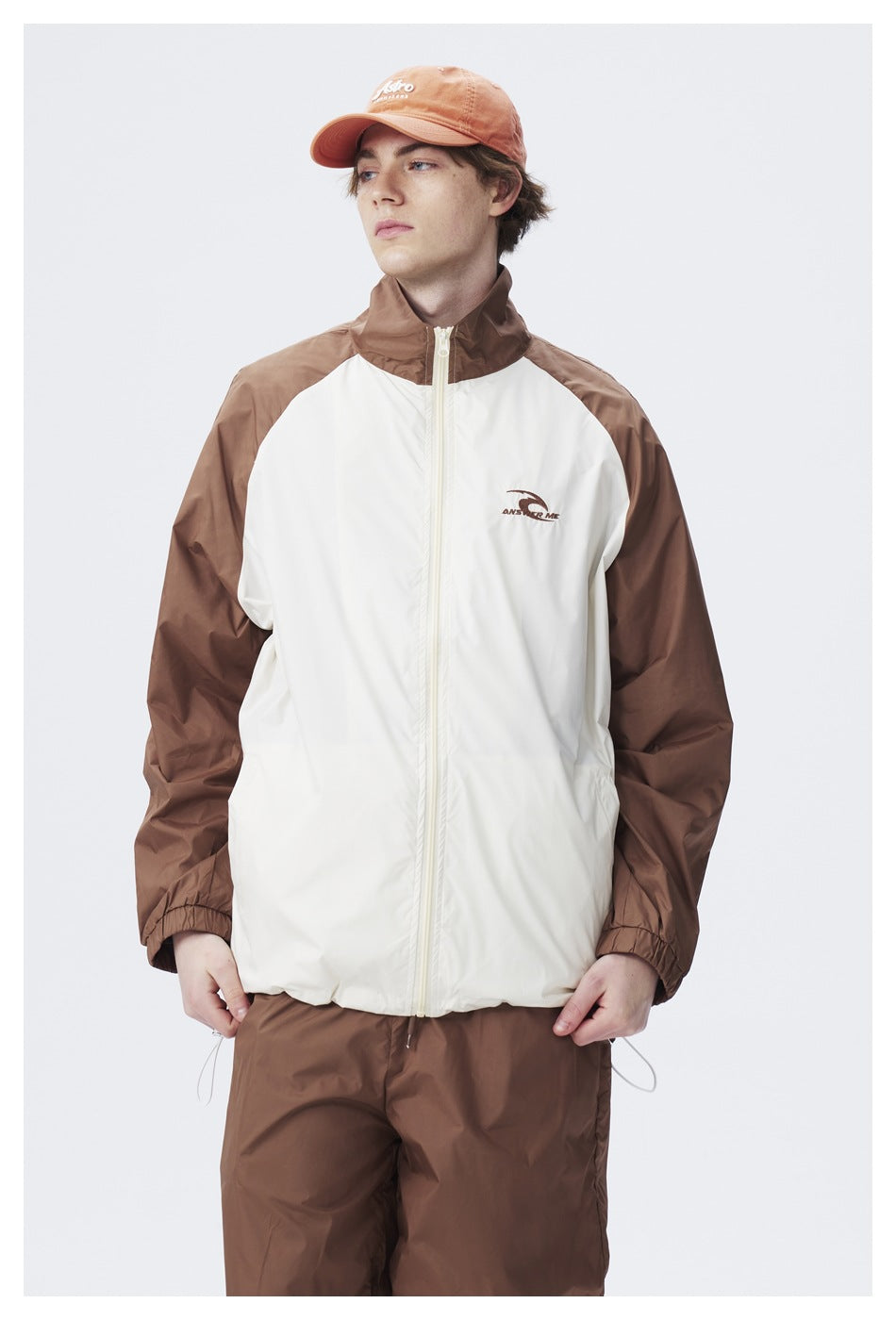 Close front view of a model in a cream-and-brown zip jacket with a raised collar and brown sleeves.
