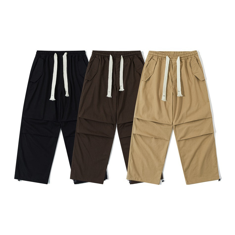 Three pairs of loose-fit pants shown from the front in black, dark brown, and tan, each with white drawstrings.