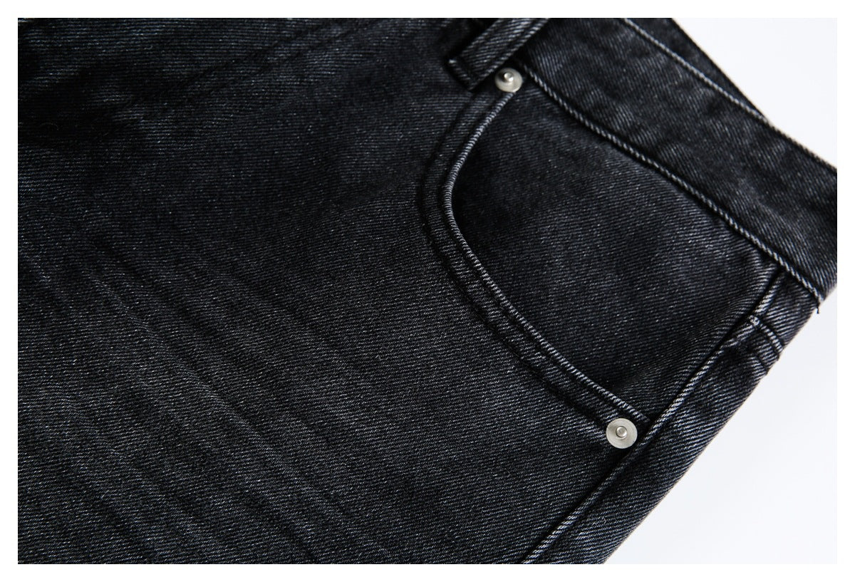 Close-up of a curved front pocket with metal rivets on black denim jeans.