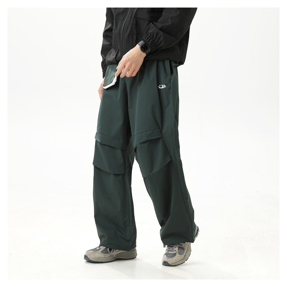 Cropped model wearing dark green wide-leg cargo pants with layered knee panels and a small logo, shown at an angle.