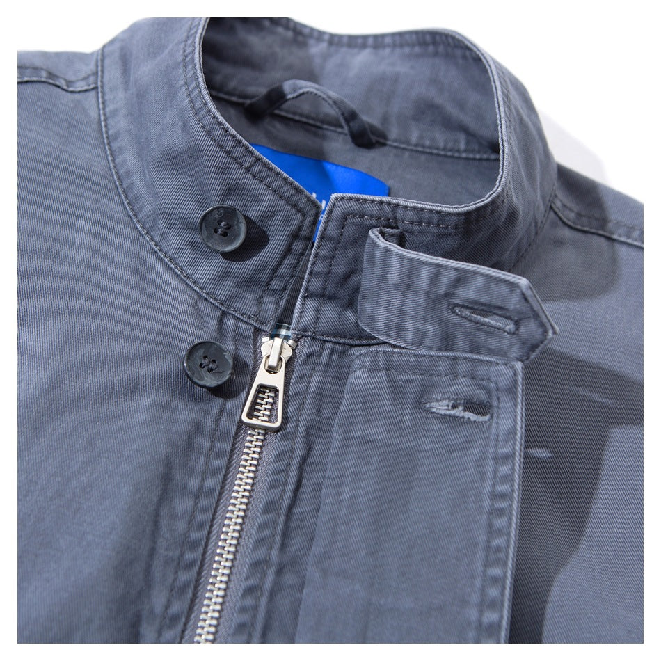 Close-up of a slate blue-gray jacket collar, front zipper, dark buttons, and flap pocket.