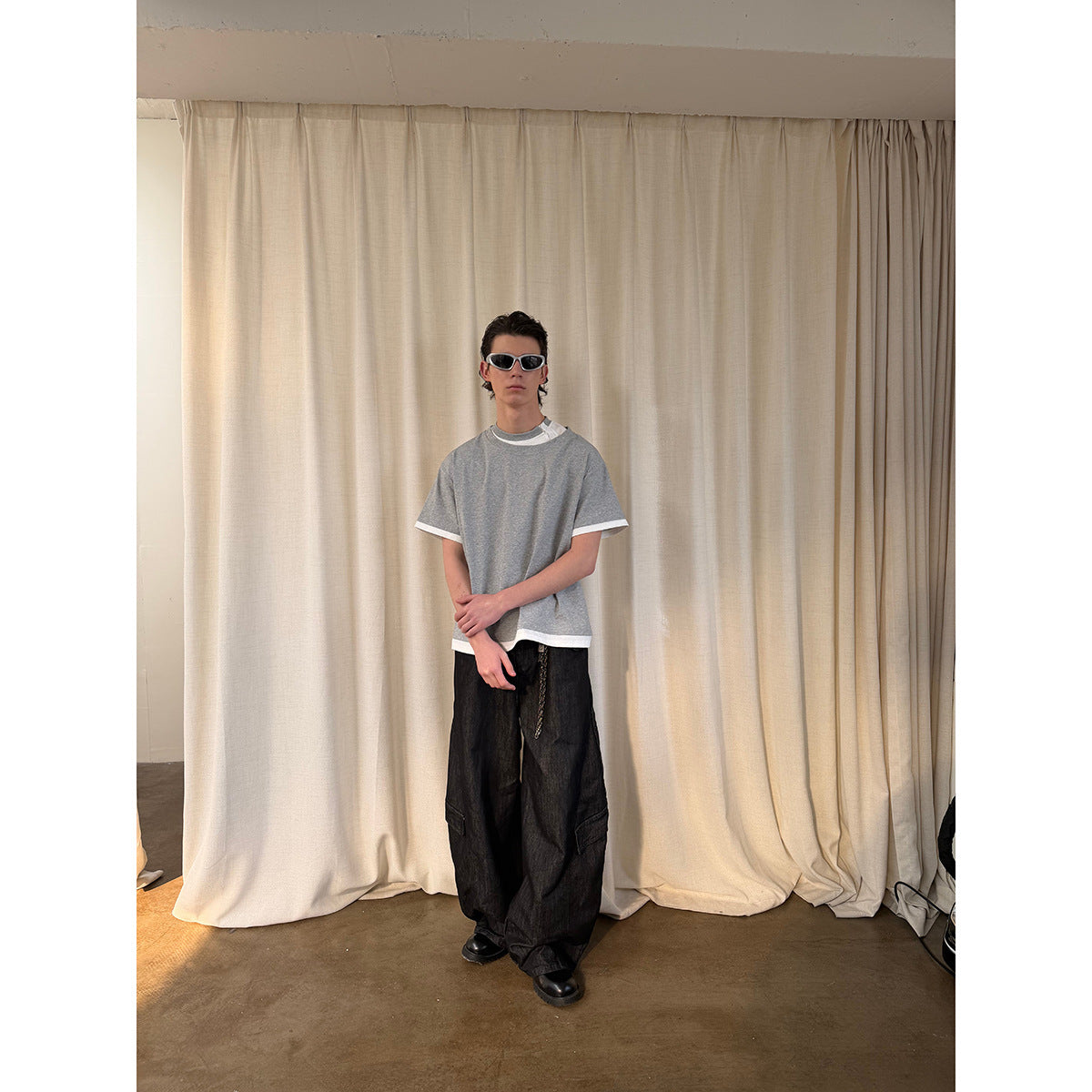 Full-length view of a model wearing a gray T-shirt with white trim, layered over a white shirt.
