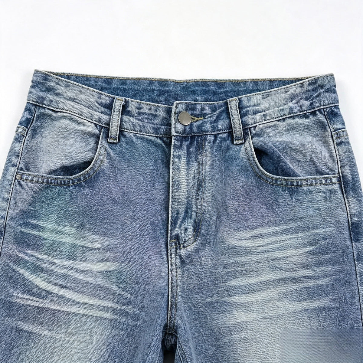 Close-up of the front of blue washed jeans, showing the waistband, button, belt loops, fly, and front pockets.