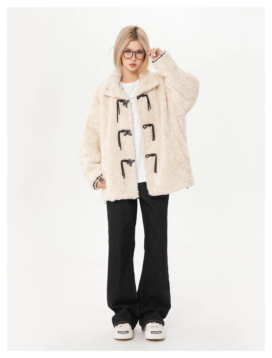Model wearing cream fleece-textured toggle jacket open over a white top with black flared jeans