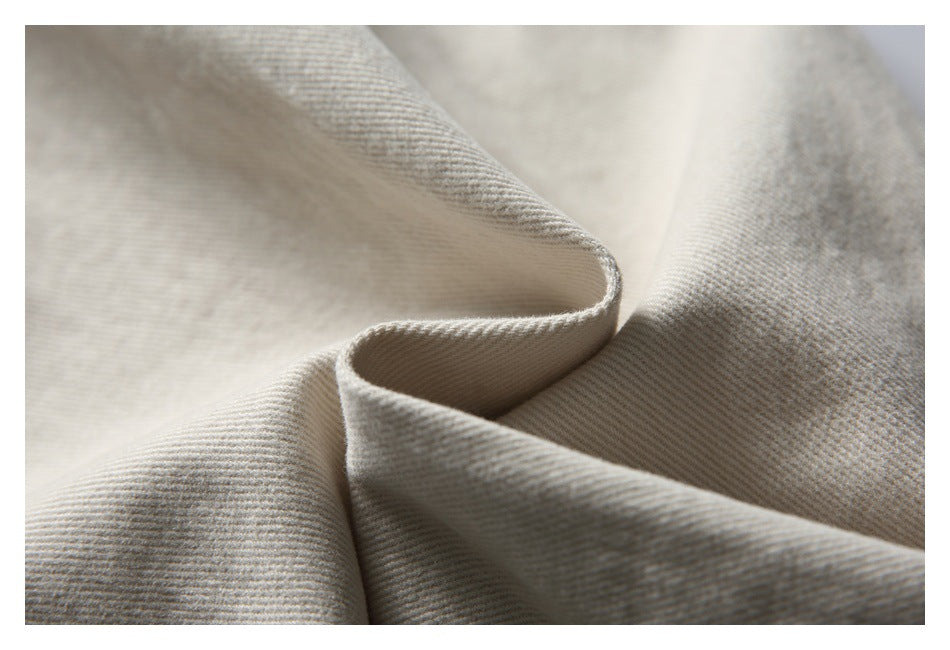 Macro view of light beige fabric folded to show its diagonal woven texture.