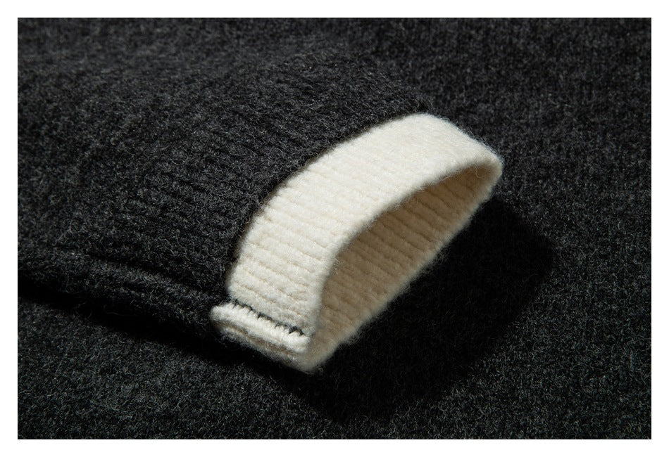 Close-up of a cream ribbed cuff turned back against the dark charcoal knit sleeve.