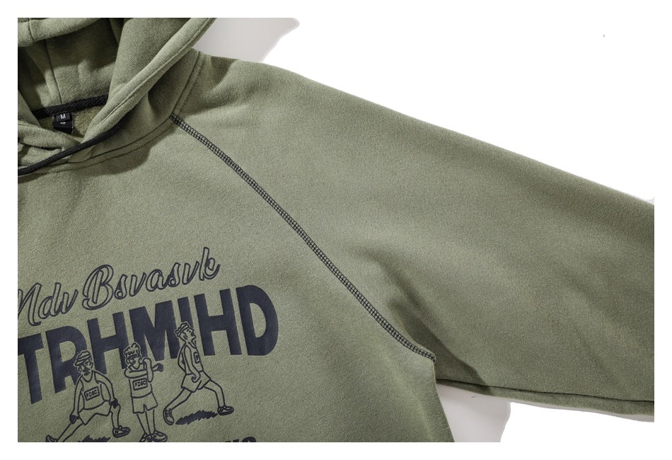 Close-up of the olive green hoodie’s hood, raglan sleeve seam, and part of its dark front graphic.