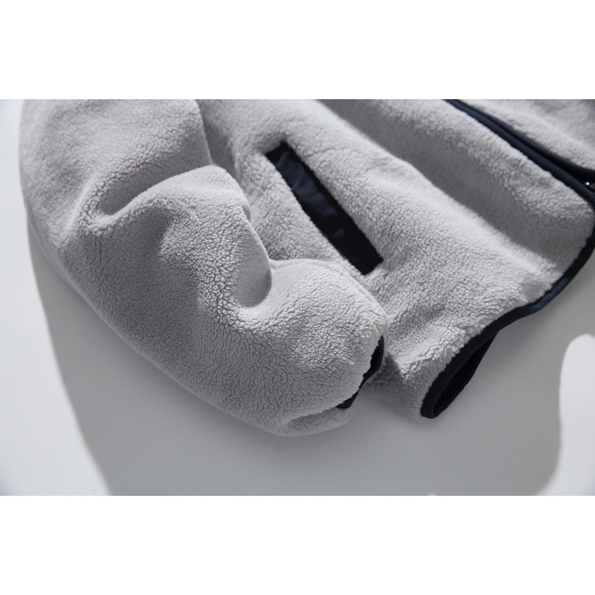 Close-up of the light gray fleece jacket's sleeve, cuff, and dark-trimmed pocket opening.