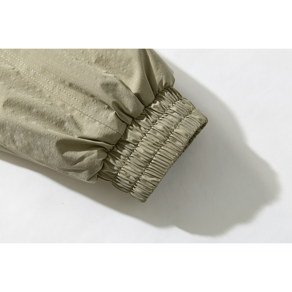 Close-up of an olive-beige jacket sleeve with a gathered elastic cuff.
