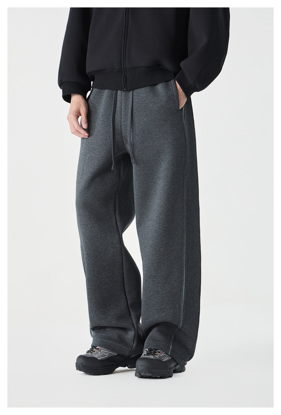Front view of a model wearing charcoal wide-leg sweatpants with a drawstring waist and seam detailing.