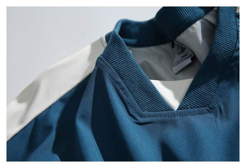 Close-up of a teal athletic top's V-neck collar with ribbed trim and a light-colored shoulder panel.