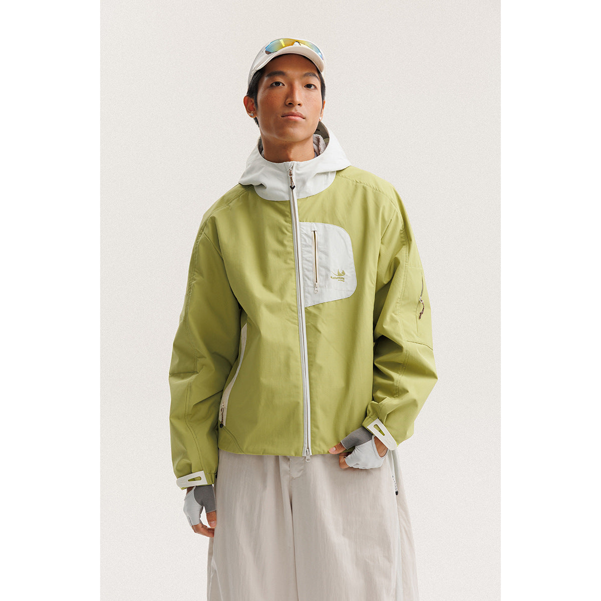 Front view of a model wearing a light green hooded jacket with white panels and a white chest pocket.