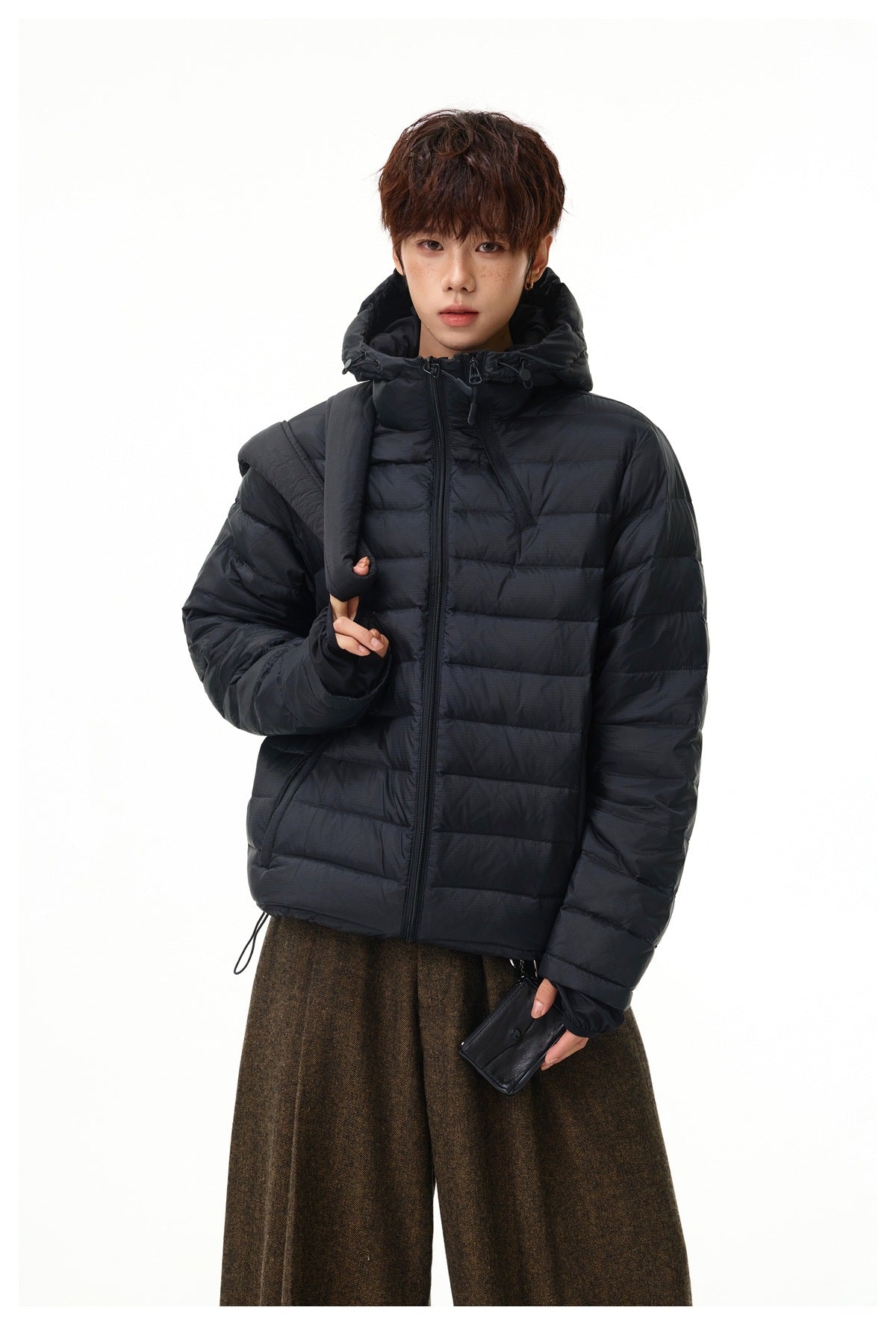 Front view of a model wearing a black quilted hooded jacket with a front zipper and adjustable hem.