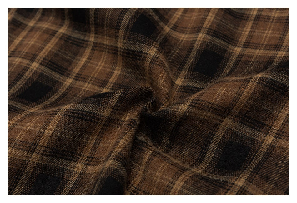 Draped brown and black plaid fabric shown close up, highlighting its woven texture.
