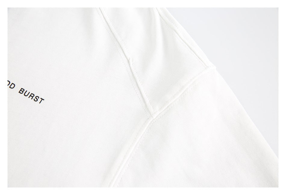 Close-up of a white shirt’s shoulder and sleeve seams, with part of the black chest print visible.