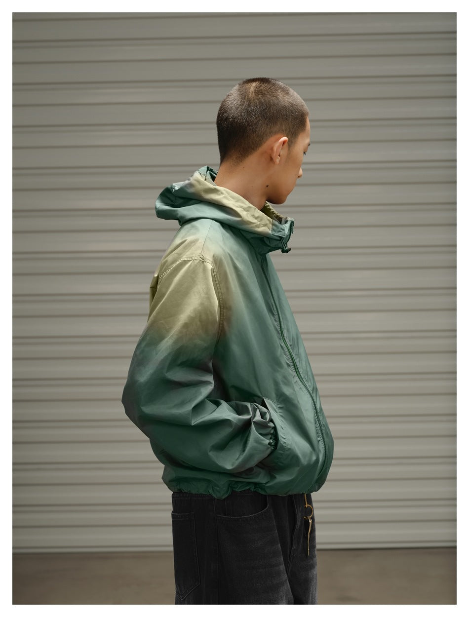 Side view of a model wearing a sage green hooded jacket with olive accents and gathered cuffs.