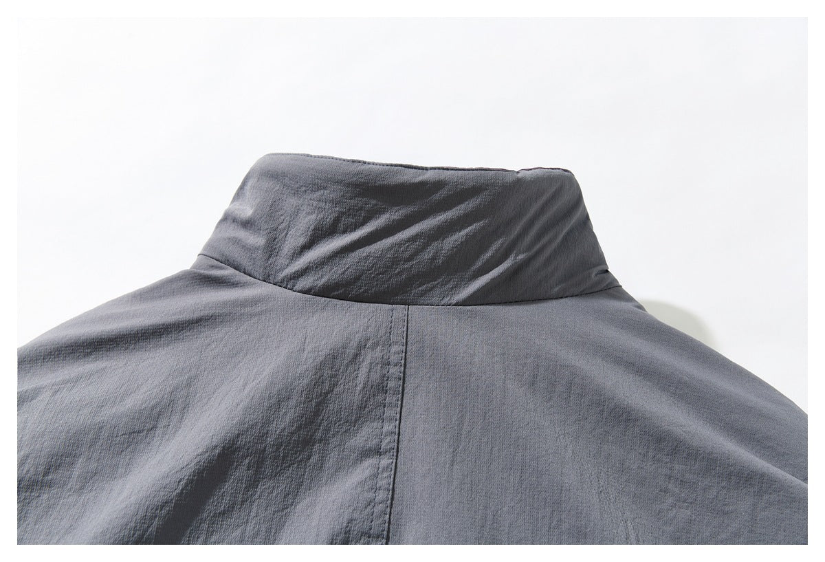 Close-up of the raised collar and center back seam of a gray jacket.
