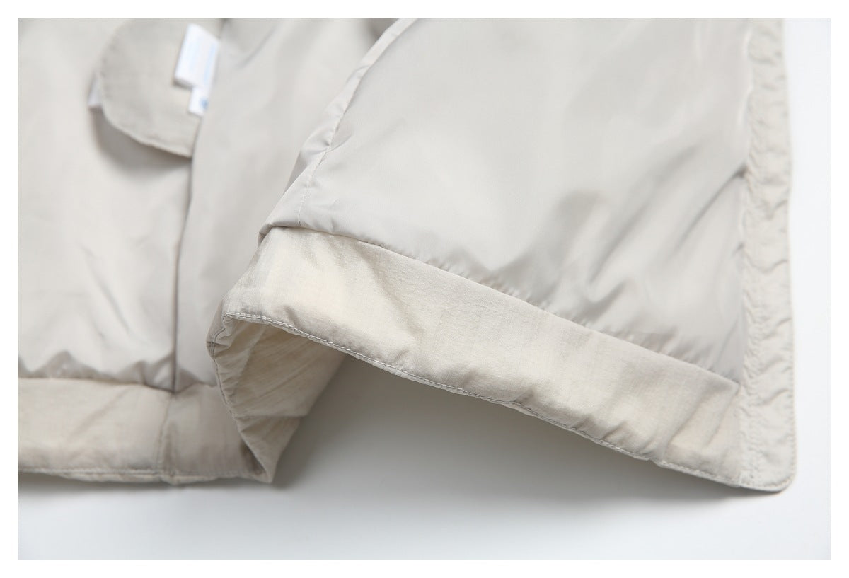 Close-up of the cream jacket's hem and seam, showing the smooth lining beside the quilted outer fabric.