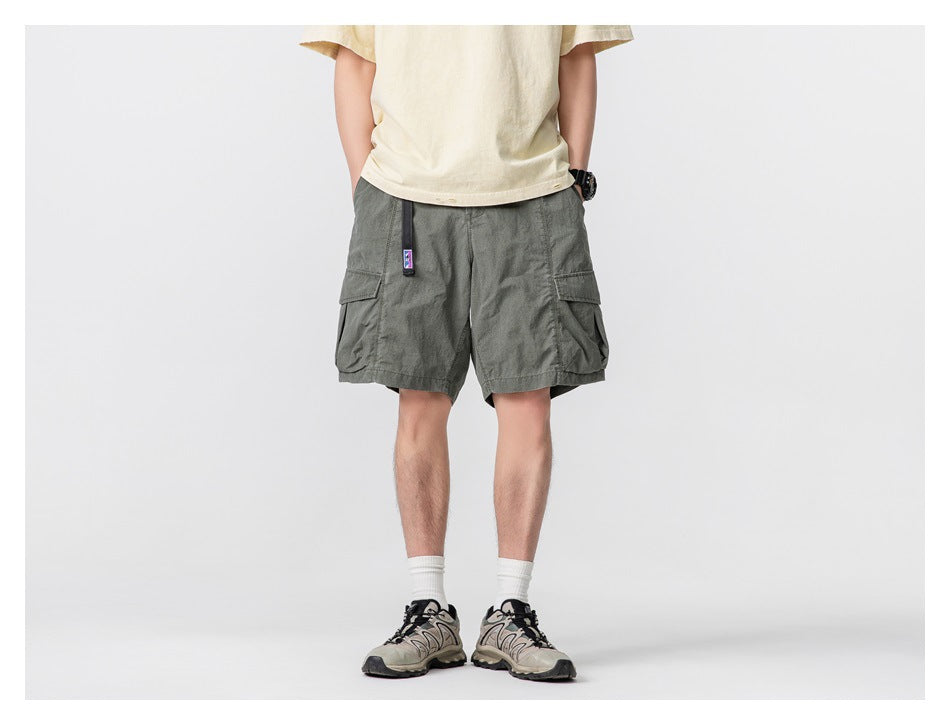 Front view of a model wearing dark gray-green cargo shorts with large side flap pockets.
