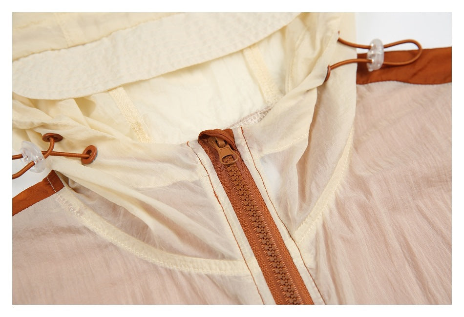 Close-up of a cream hood and rust-brown zipper on a rust and pale pink color-block jacket.