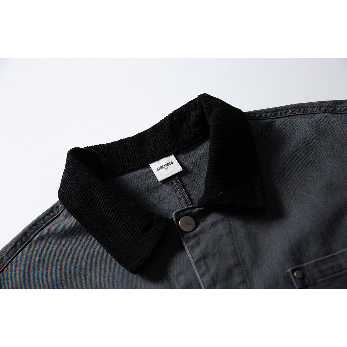 Close-up of a charcoal jacket collar with a black ribbed collar, dark button, and small neck label.