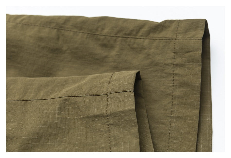 Close-up of stitched edges and a folded hem on olive-khaki pants.