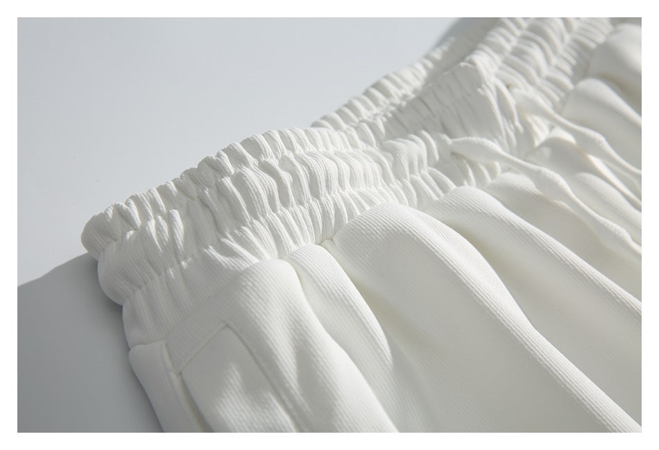 Close-up of the gathered elastic waistband and fabric folds on the white pants.
