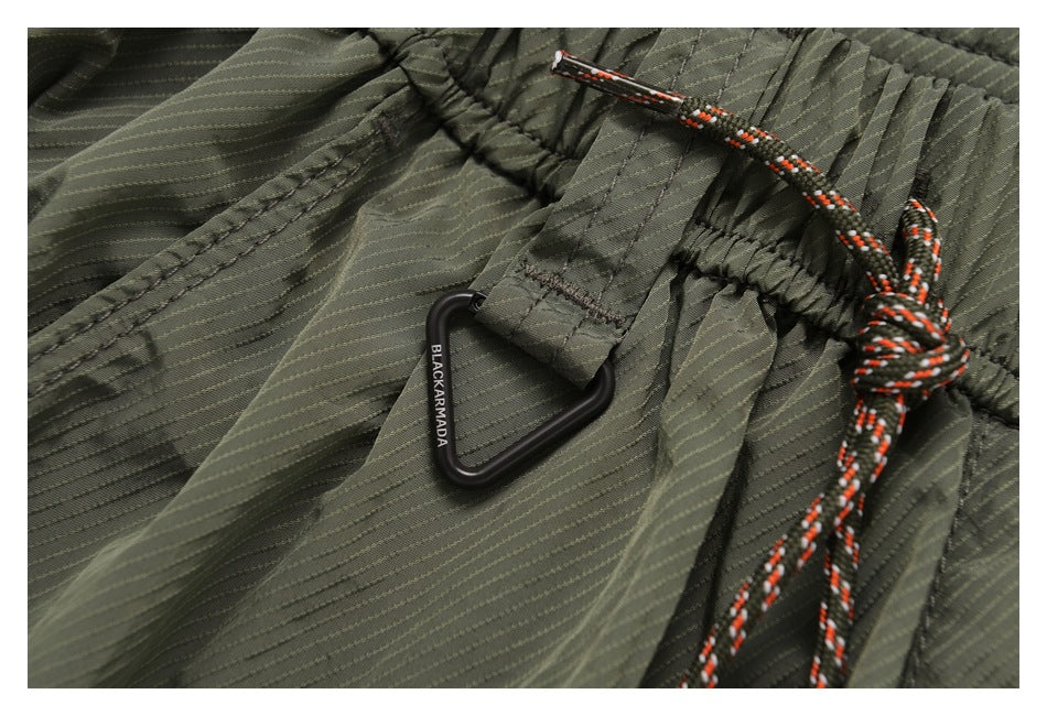 Close-up of the olive shorts waistband with a braided drawcord and black triangular clip.