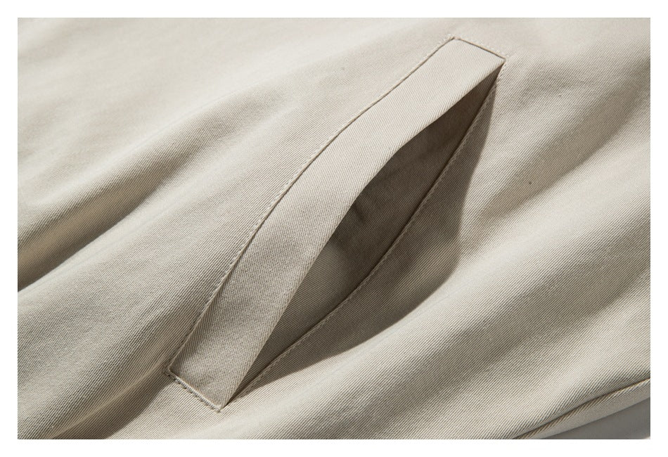 Close-up of a slanted welt pocket on beige garment fabric.