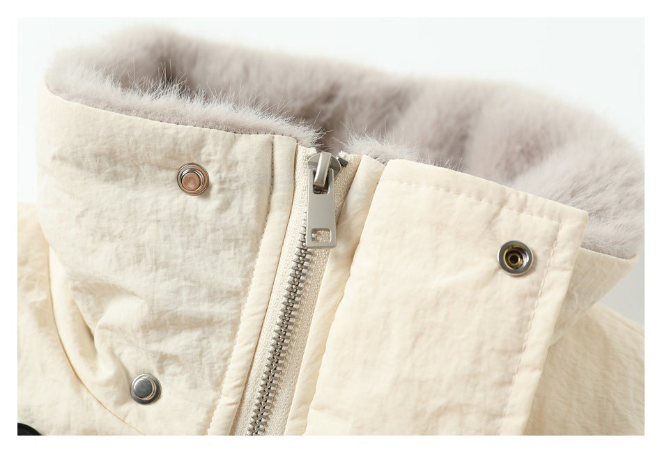 Close-up of a cream garment's metal front zipper, snap fasteners, and plush lining.