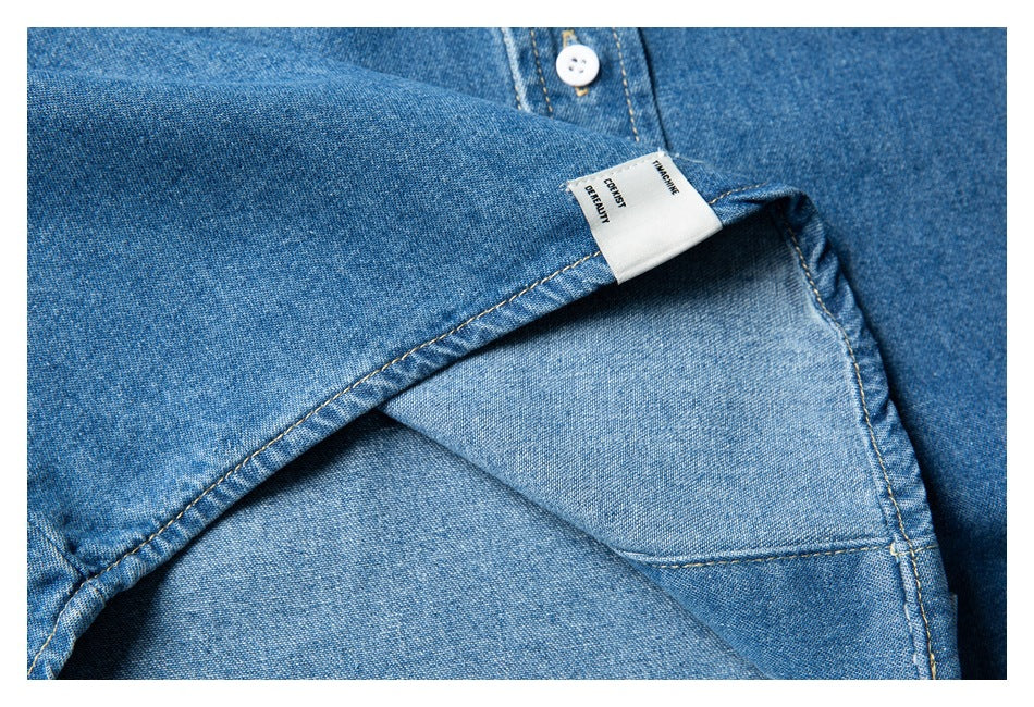 Close-up of the inside of a blue denim shirt with a sewn-in label and visible stitching.