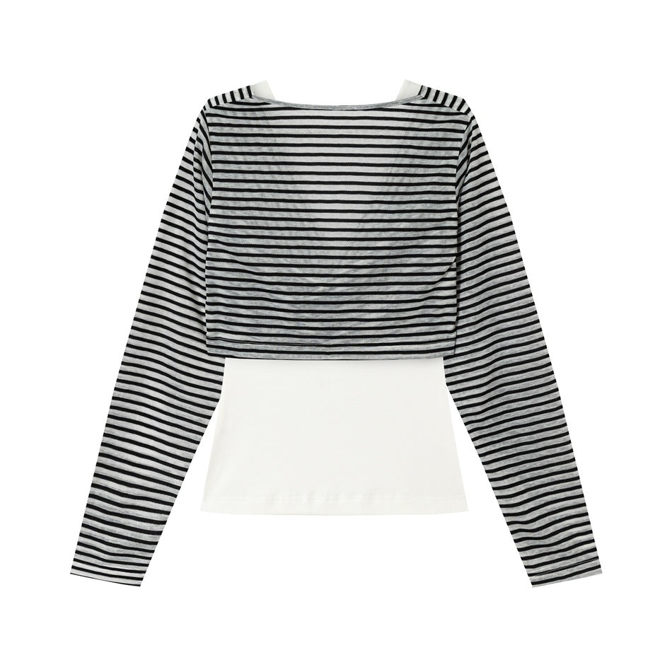 Back view of black and gray striped long-sleeve cropped top layered over a white underlayer, flat lay