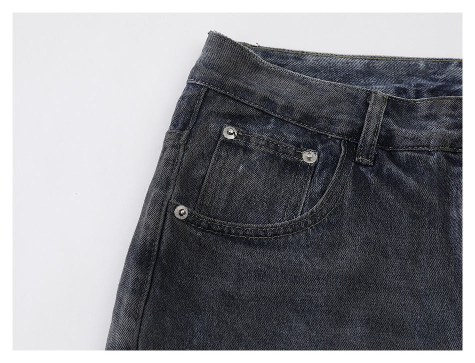 Close-up of dark washed jeans showing a front coin pocket with metal rivets and contrast stitching.