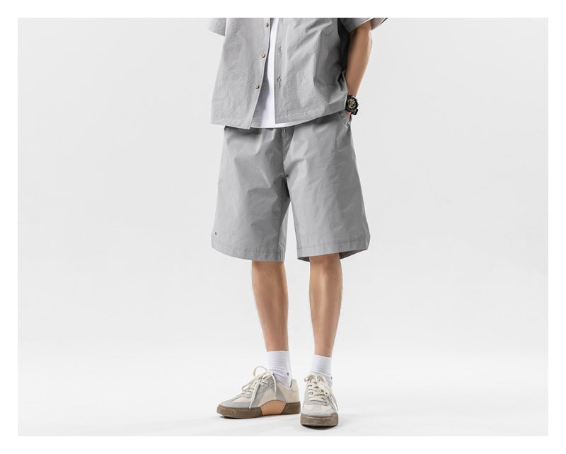 Cropped model wearing a light gray short-sleeve button shirt and matching knee-length shorts.