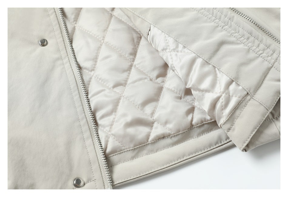 Close-up of a light beige jacket interior with diamond quilting, a zipper, snap fasteners, and a folded edge.