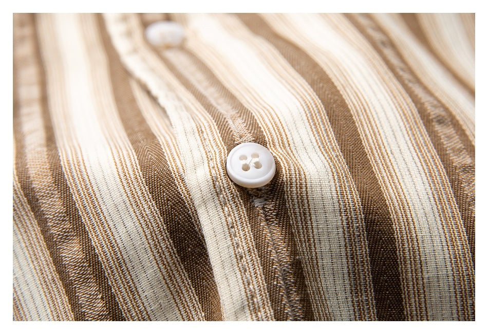 Macro view of a white shirt button against cream, tan, and brown striped fabric.